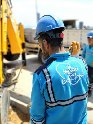 Construction workers operating excavator at a road site, ensuring progress and safety.