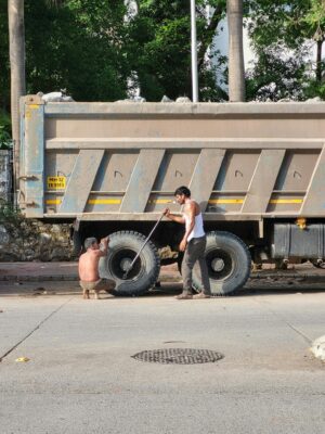 Two men fixing a truck on a city street, highlighting transportation and maintenance.