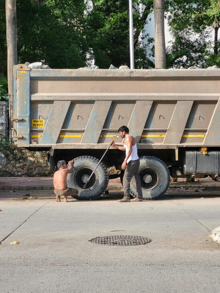 Two men fixing a truck on a city street, highlighting transportation and maintenance.